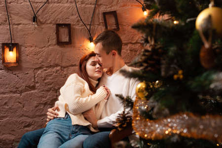 A guy with a girl is celebrating Christmas. A loving couple enjoys each other on New Year's love story. Christmas decorations in the photo studio. Posing for modelsの写真素材