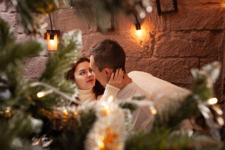 A guy with a girl is celebrating Christmas. A loving couple enjoys each other on New Year's love story. Christmas decorations in the photo studio. Posing for modelsの写真素材