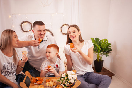 A happy family smiles and Eats sweets. Delicious pies and pastries with cherries, mushrooms. Dad, mom and two kids have breakfast, have lunch on the bed.の写真素材