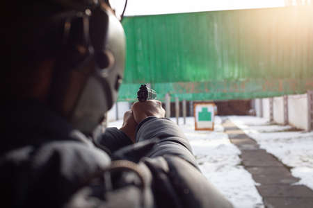 A man with headphones is aiming at the target. Tire outside the door. Winter. Sports entertainment,...