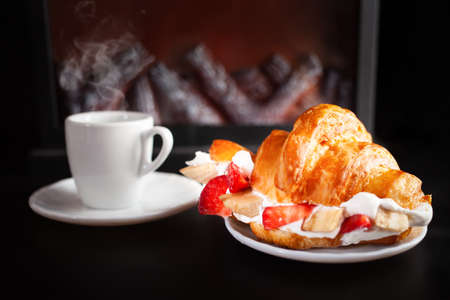 Minimalism, food on a background. Empty text space, mocap. fireplace, fire, tea and croissant with...