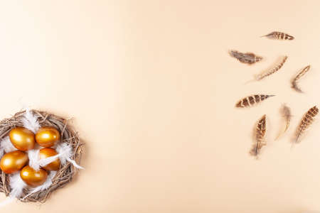 Empty space for text, a banner of happy Easter. Painted golden eggs, white feathers. copy space flat lay top view Nestの写真素材