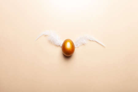 Empty space for text, a banner of happy Easter. Painted golden eggs, white feathers. copy space flat lay top view Flying eggs with wings fly away from the nestの写真素材