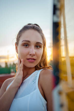 Portrait of a beautiful American woman. Sports tennis court, outdoor recreation. Fitness body, weight loss, active lifestyle, rest after training. Sunset, summer. racketの写真素材