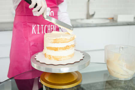 A gloved pastry chef decorates cake with white chocolate. Beautiful homemade cakeの写真素材