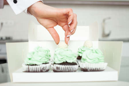The confectioner decorates cupcakes, homemade cooking, sweets.の写真素材