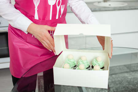 The confectioner packs cupcakes in box, sending to customer, home business, entrepreneurship.の写真素材