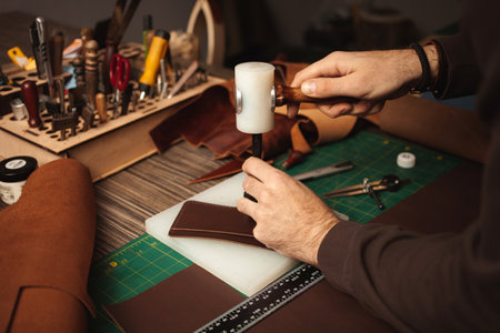 makes holes with hammer. tanner makes leather purse. DIY instruction. Eco production, entrepreneur.