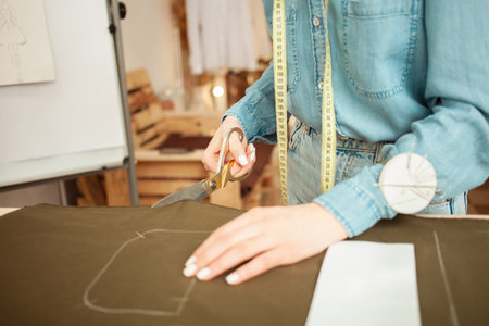 Seamstress cut out from fabric details of future clothes, pattern. Fashionable sewing studio, small business, indoors.の写真素材