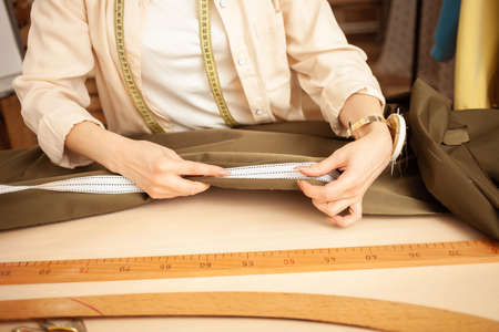 seamstress in atelier, portrait at work. Table with fabric and sewing tools, indoors.の写真素材