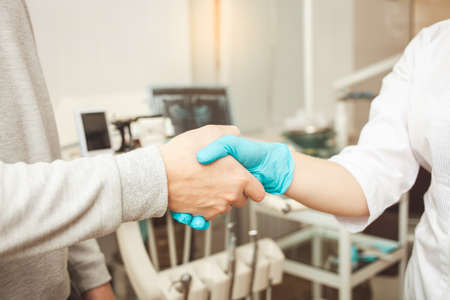 doctor and patient shake hands, happy and satisfied with cooperation, friendly dentist, professional service.の写真素材