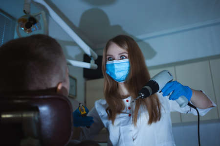 creepy dentist scares client with drill, fear and horror, Halloween. man is afraid of doctor, wants to escape, seeks salvation and help. Screwdriverの写真素材