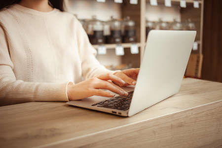 female seller in tea shop counts profits, Writes sales, keeps accounting records, small business, an entrepreneur. laptop, online, internetの写真素材