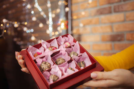 Box with dry tea, shop, goods in womens hands, gift packaging red.