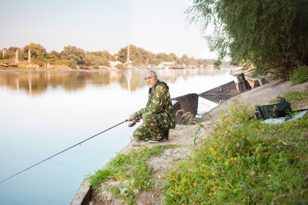senior concept. The pensioner fishes on the river in his spare time. A useful hobby, outdoor activities in old age. copy space. rusty boatの写真素材