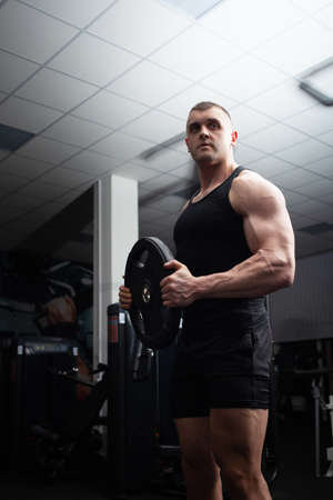 Portrait of a handsome man in the gym. Coach, athlete, bodybuilder, muscular sexy body, darkness....