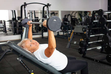 elderly woman with gray hair plays sports in gym. Active healthy lifestyle, pensioner, senior...