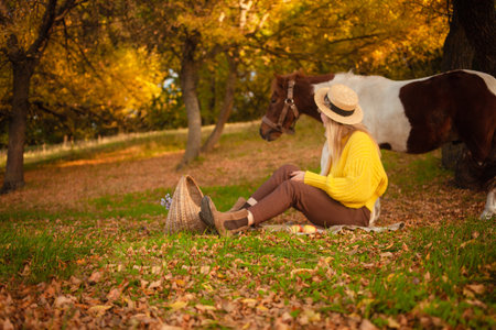Beautiful woman and pony horse in autumn forest, sunset light, portrait, outdoor recreation, love and friendship. backgroundの写真素材