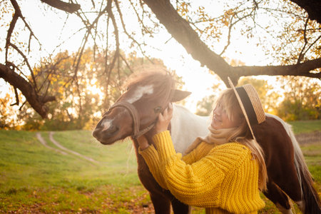 Beautiful woman and pony horse in autumn forest, sunset light, portrait, outdoor recreation, love and friendship. scratchingの写真素材