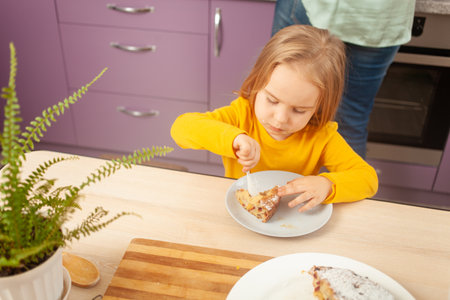 Portrait of little girl of three years old, kitchen, pie, dabbling, funny. eats the pie on her ownの写真素材