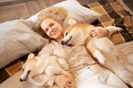 woman and dogs lie on bed, family, smiling. Relax, spend time together, enjoy and have fun. lifestyle, everyday life. look at cameraの写真素材