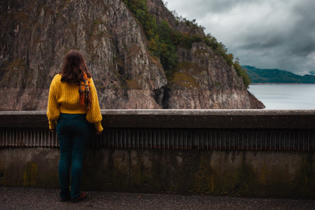 woman looks at mountains, beautiful landscape, cloudy rainy weather, bad. Loneliness, travel, human and nature. Alone with myself. vidraru damの写真素材