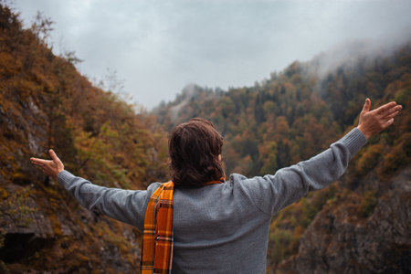 man looks up at mountains, lonely, pensive, autumnal landscape, rainy bad cloudy weather, alone. Travel and tourism. freedomの写真素材