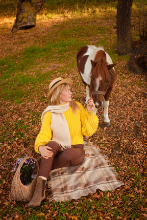 Beautiful picture, autumn nature, woman and horse, concept of love, friendship and care. background. picnicの写真素材
