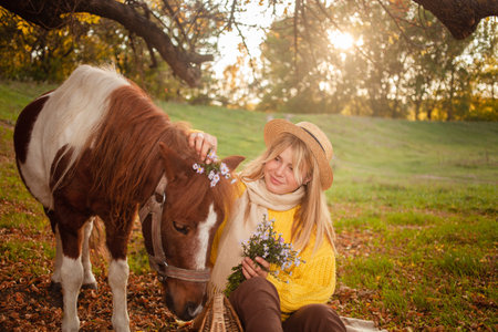 Beautiful portrait, woman and pony, spotted horse, in autumn forest, pleasant colors, background. concept of love, tenderness, friendship. wreath of flowersの写真素材