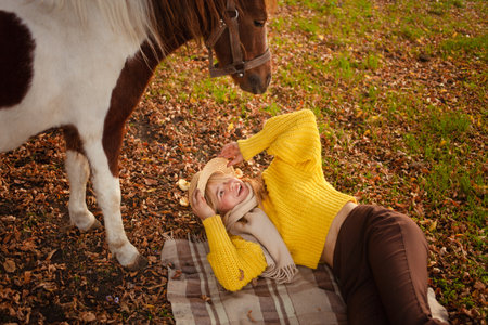 Beautiful portrait, woman and pony, spotted horse, in autumn forest pleasant colors background. concept of love, tenderness, friendship. Laughsの写真素材