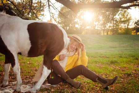 Beautiful portrait, woman and pony, spotted horse, in autumn forest pleasant colors background. concept of love, tenderness, friendship. laughs, funnyの写真素材