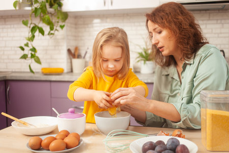 Grandmother and granddaughter cook in kitchen in middle, family pastime, leisure. woman and child make cake in purple, lavender kitchen. plum pieの写真素材