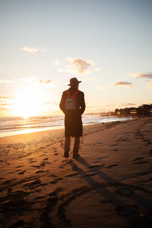 Relaxed atmosphere as man strolls beach at twilightの写真素材