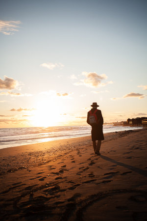 Relaxed atmosphere as man strolls beach at twilightの写真素材