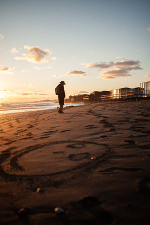 Solitary figure enjoys beach walk under setting sunの写真素材