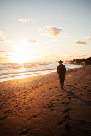 Calm evening man walks by ocean under colorful skyの写真素材