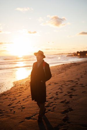 Coastal tranquility man walks along shore at duskの写真素材