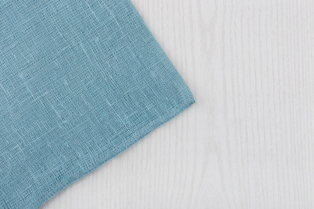Napkin from left side wooden table. White blue background. Soft blue woven linen fabric texture / white wood texture.の写真素材
