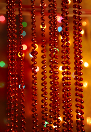 Beaded garlands decor.  Red and orange christmas bokeh above firtree.  Abstract Christmas background.の写真素材