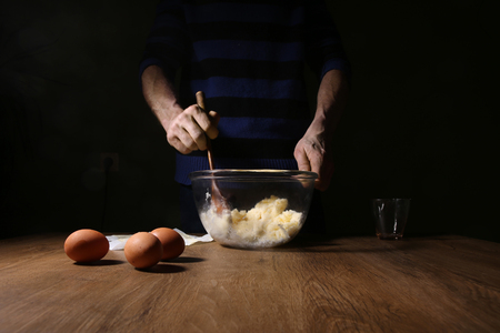 Man hands breaking an egg. Step of making cooking cake, preparing dough. Ingredients: butter, sugar, eggs.の写真素材