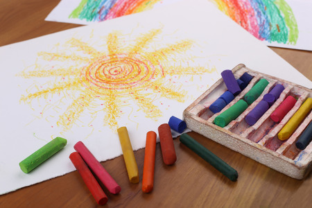 Drawing with pastel crayon. Crayon pieces and drawings on table.の写真素材