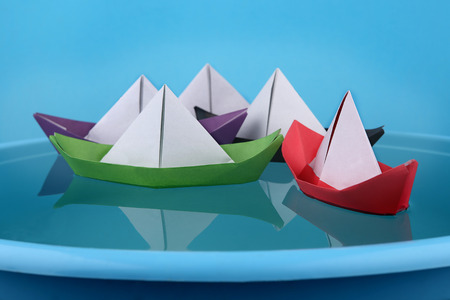 Paper boats game. Origami paper ships sailing on blue water surface.の写真素材