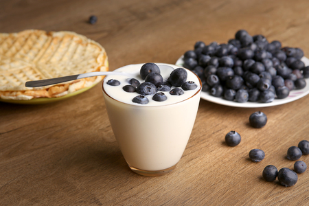 Yogurt with blackberries in a glass. Yogurt with blueberries and heart shaped pancakes on wooden table.の写真素材
