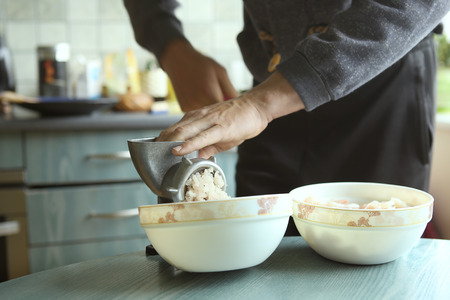 Man mincing fish with grinder. Preparation of minced fish pike in kitchen.の写真素材