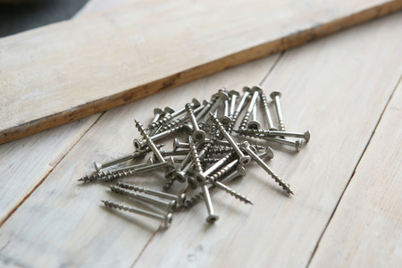 Wood screws on wooden planks. Wood screws pile on aged wooden surface.の写真素材