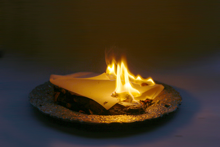 Document burning in vintage plate. Paper sheet with text burning in fire.