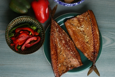 Smoked mackerel in plate and sliced red sweet paprika in bowl, top view. Raw sweet pepper and hot...