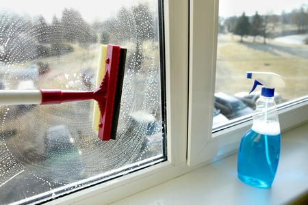 Glass squeegee and bottle of window cleaner. Cleaning windows with a squeegee.の写真素材