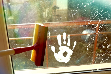 Hand print on dirty window and squeegee cleaning the glass. Cleaning windows with a squeegee.の写真素材