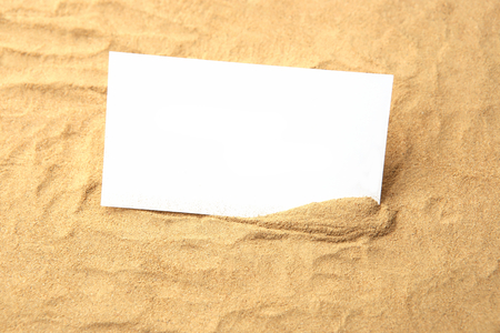 Blank card in sand. Empty paper on beach sand.の写真素材